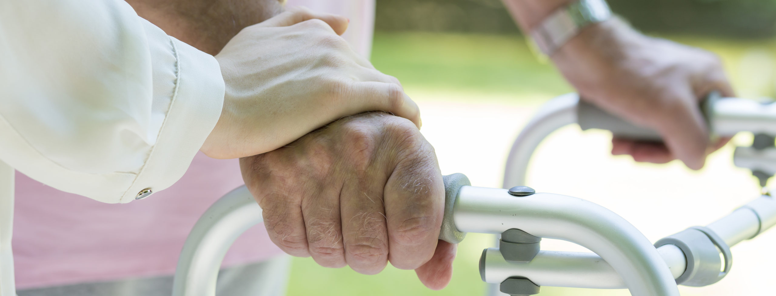 Man's hands holding the walking frame with carer support